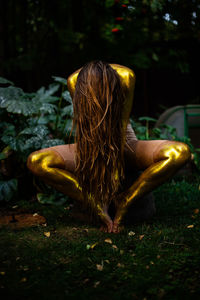 Young woman with golden skin sitting in the garden