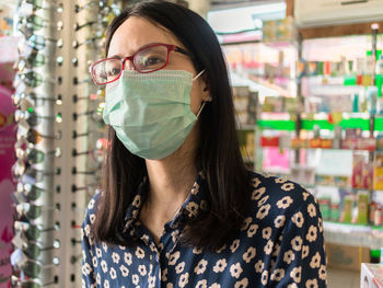 Young woman wearing surgical mask at shop