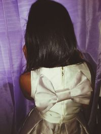 Rear view of girl sitting at home