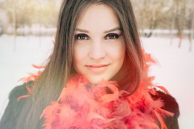 Portrait of smiling young woman wearing feather boa during winter