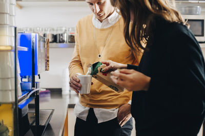 Young woman holding camera while standing in store