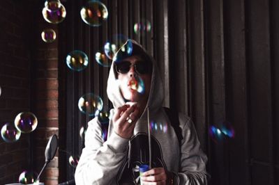 Man blowing bubbles while standing against wall