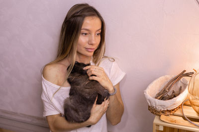 Portrait of smiling young woman standing against wall