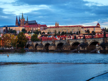 Arch bridge over river against buildings in city