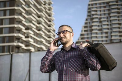 Full length of man standing on mobile phone in city