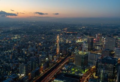 High angle view of illuminated city buildings against sky during sunset