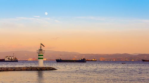 Boats in sea at sunset