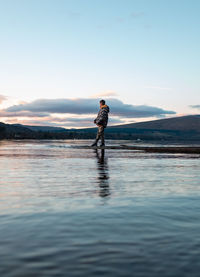 Side view of man standing in sea against sky