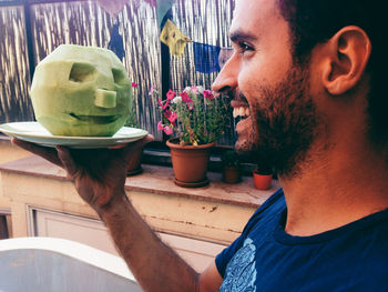 Happy young man holding carved cantaloupe in plate