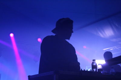 Low angle view of silhouette man against illuminated blue sky at night