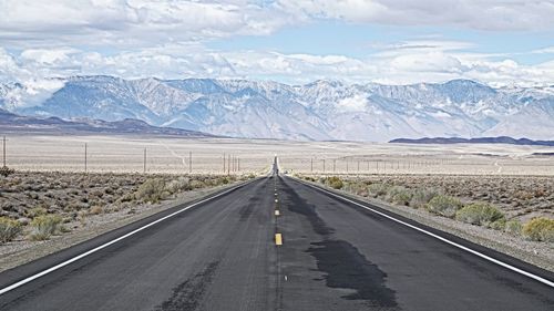 Road by mountains against sky