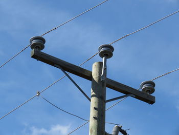 Low angle view of birds perching on cable against sky