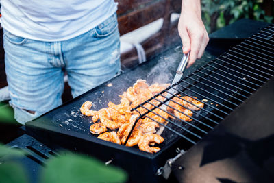 Grilling shrimp on skewer on outdoor grill. grilled shrimps on the flaming grill. man hand using