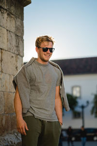 Young man wearing sunglasses standing against clear sky