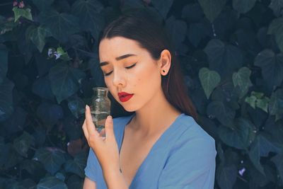 Young woman crying while standing against plants