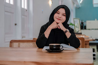 Young woman using mobile phone at table