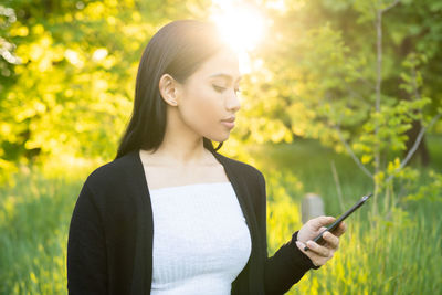 Young woman standing against plants