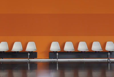 Empty chairs and table against orange wall