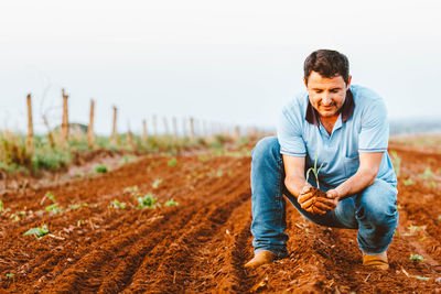 Smiling man holding seedling at farm