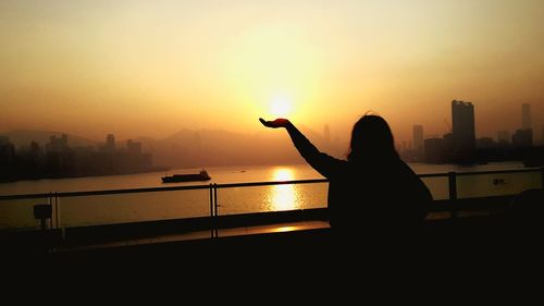 Silhouette woman against sea during sunset