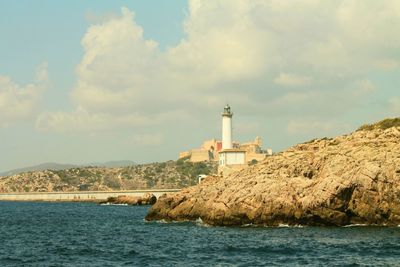 Scenic view of sea with lighthouse against cloudy sky