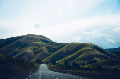 Country road along landscape against sky