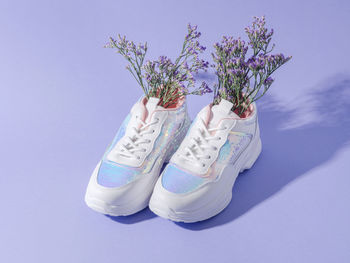 White female sneakers with sequins with flowers inside on purple