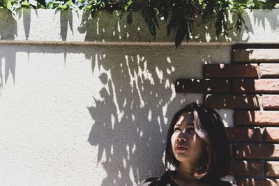 Portrait of young woman against wall