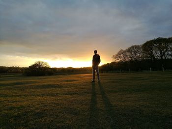 Full length of man standing on field against sky during sunset