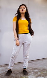 Portrait of beautiful woman standing against yellow wall