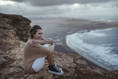 Full length of man sitting on rock