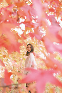 Full length of woman standing by pink flower