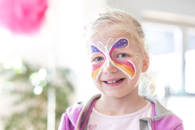 Portrait of smiling girl with painted butterfly on face