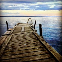 Pier on sea against cloudy sky