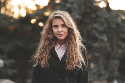 Portrait of young woman standing in front of trees