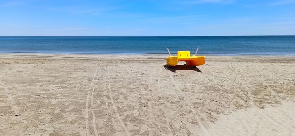 Deck chairs on beach against sky