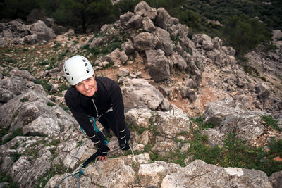 Concept: adventure. climber woman with helmet and harness. looking at camera happy. anchored to the high natural wall. smiling. via ferrata in the mountains.