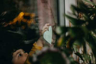 Girl sticking heart shape paper on window