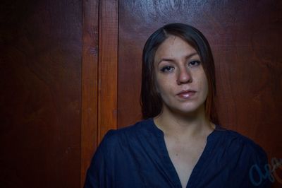 Portrait of young woman standing against door