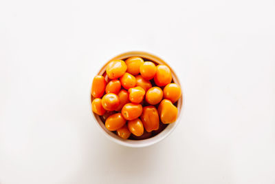 Directly above shot of orange eggs in bowl against white background