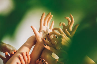 Cropped hands of female friends with arms raised against wall