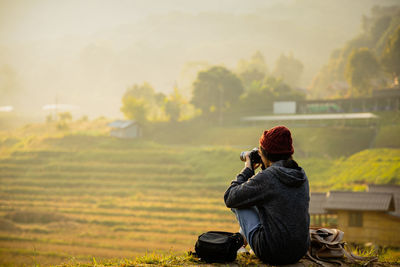 Rear view of man photographing on field