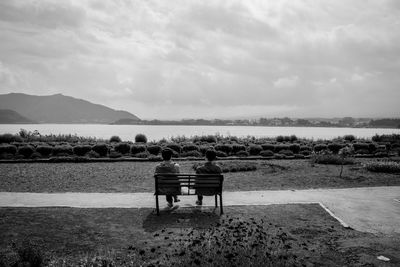 Man sitting on bench against sky