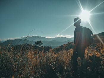 Woman standing on field against bright sun