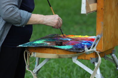 Midsection of person holding multi colored umbrellas painter, paint, brush, paint, weather