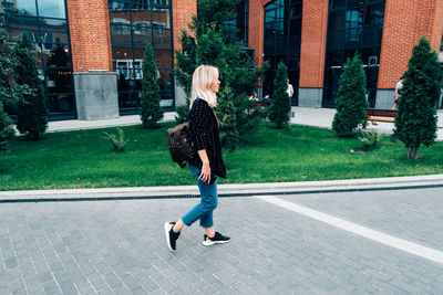 Full length rear view of woman walking on street in city