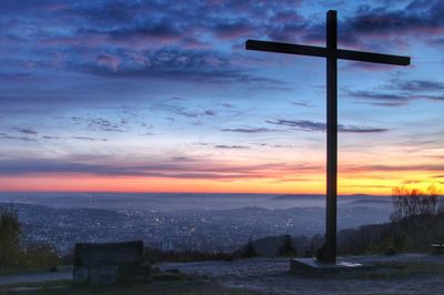 Silhouette cross against sky during sunset