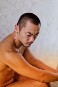 High angle view of naked mid adult man sitting by wall in room