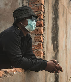 Side view of man wearing hat against wall