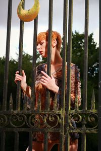 Redhead woman standing by metallic gate